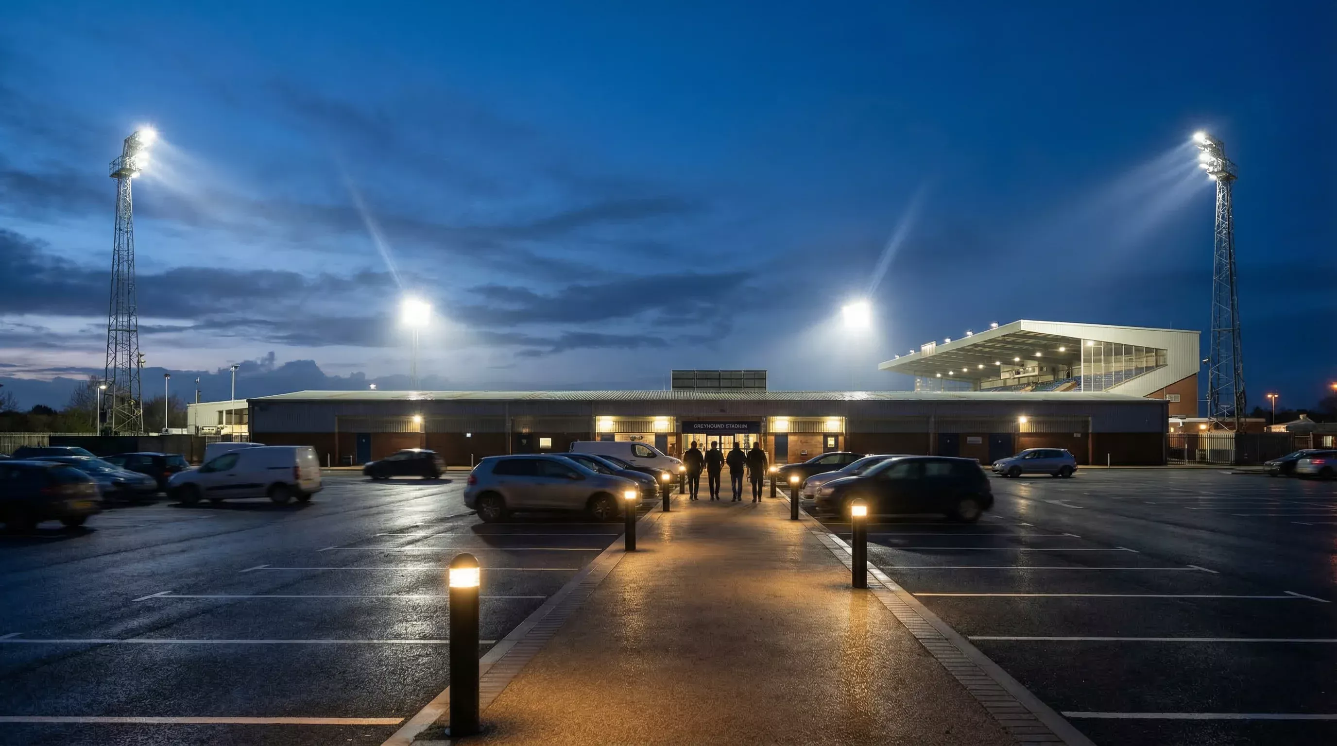 Car park at Sunderland Greyhound Stadium in the evening with the floodlit stadium visible in the background